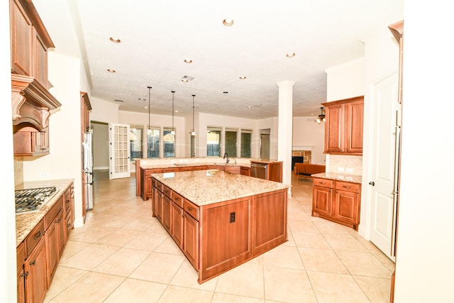 kitchen with a tile fireplace, ceiling fan, decorative light fixtures, a kitchen island, and appliances with stainless steel finishes