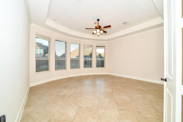 tiled empty room featuring plenty of natural light, ceiling fan, crown molding, and a tray ceiling