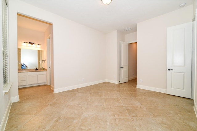 unfurnished bedroom with light tile patterned floors and connected bathroom