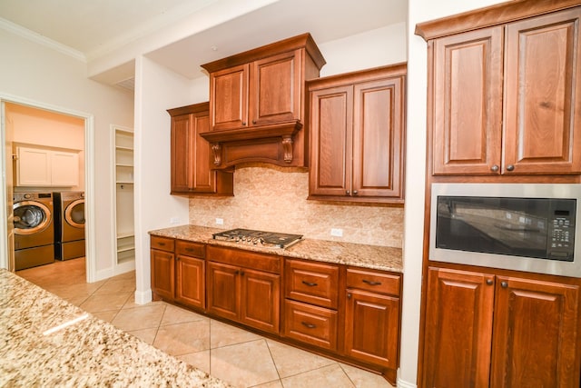 kitchen with appliances with stainless steel finishes, tasteful backsplash, crown molding, light tile patterned floors, and independent washer and dryer