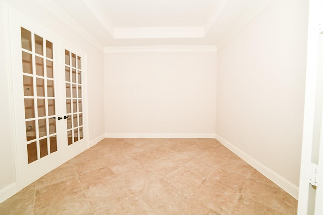 spare room with a raised ceiling, crown molding, and french doors