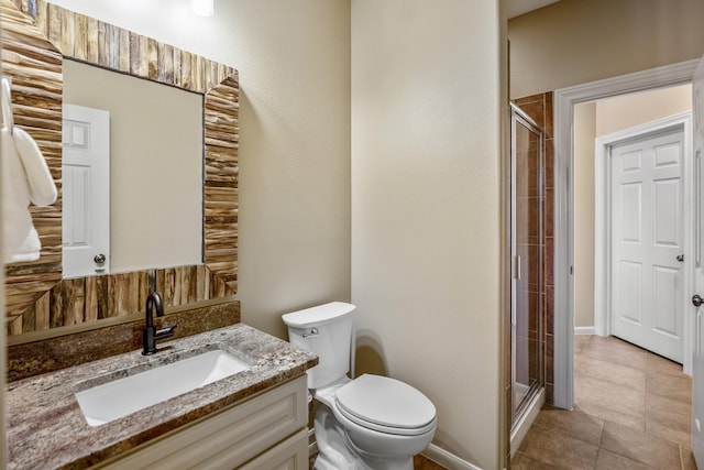 bathroom with an enclosed shower, vanity, toilet, and tile patterned floors