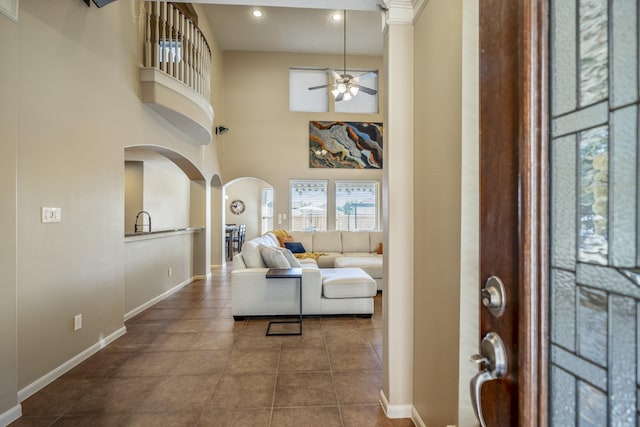 foyer entrance with a high ceiling, dark tile patterned floors, and ceiling fan