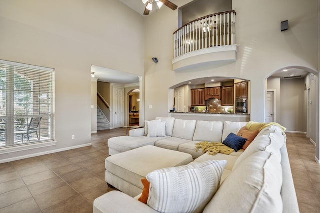 tiled living room with ceiling fan and a towering ceiling