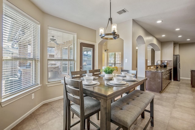 dining space featuring sink, light tile patterned floors, and a notable chandelier