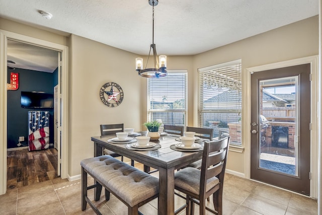 dining area featuring light tile patterned floors, a textured ceiling, and a notable chandelier