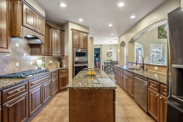 kitchen with tasteful backsplash, stainless steel appliances, sink, a center island, and hanging light fixtures