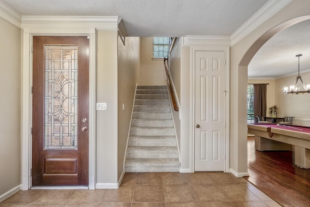 entryway with a wealth of natural light, light tile patterned flooring, and ornamental molding