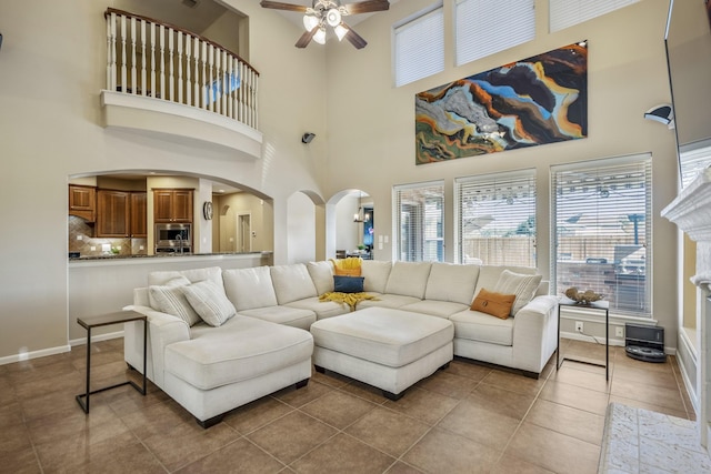 tiled living room featuring ceiling fan and a towering ceiling