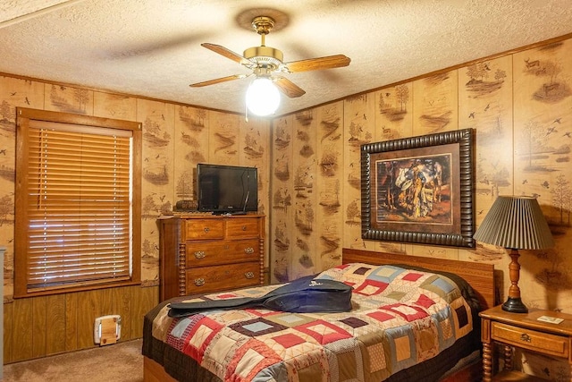 bedroom with ceiling fan, wood walls, carpet floors, and a textured ceiling