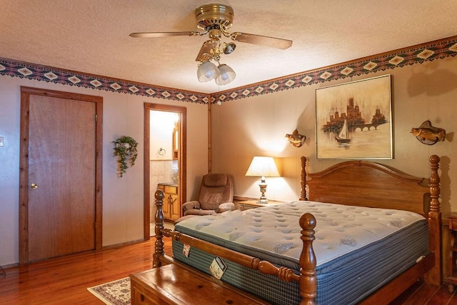 bedroom with ceiling fan, wood-type flooring, and a textured ceiling