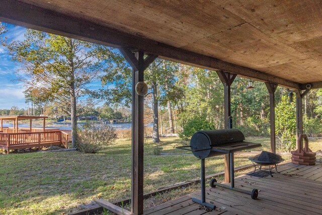 wooden terrace with a yard and a water view