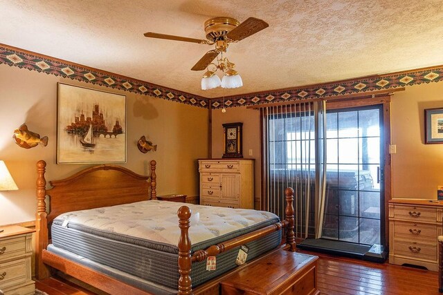 bedroom with a textured ceiling, ceiling fan, and dark hardwood / wood-style floors