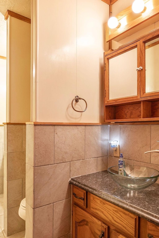 bathroom featuring vanity, tasteful backsplash, toilet, and tile walls