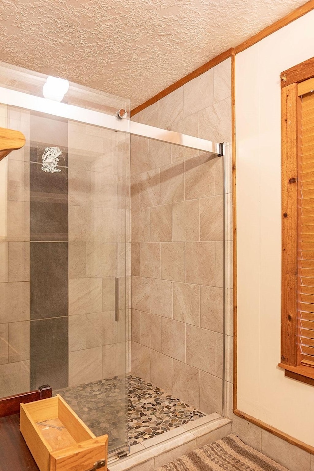 bathroom with a shower with door and a textured ceiling