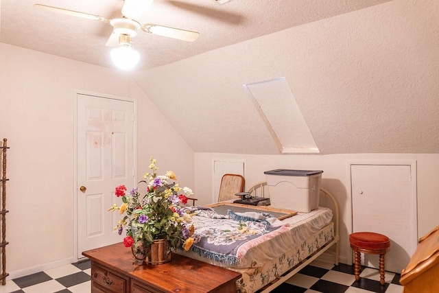 bedroom with ceiling fan, lofted ceiling, and a textured ceiling