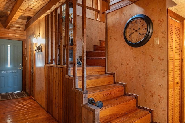 staircase featuring beamed ceiling, wood-type flooring, wood walls, and wood ceiling