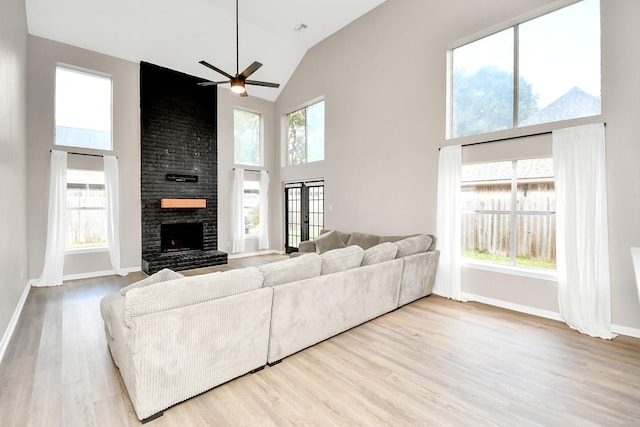 living room featuring ceiling fan, a fireplace, high vaulted ceiling, and light hardwood / wood-style floors