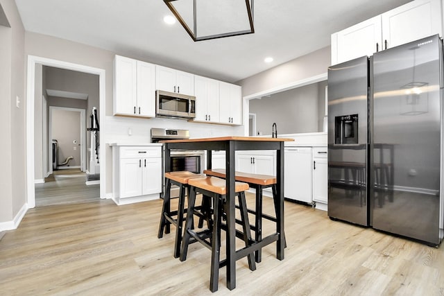 kitchen featuring white cabinets, light hardwood / wood-style floors, and appliances with stainless steel finishes