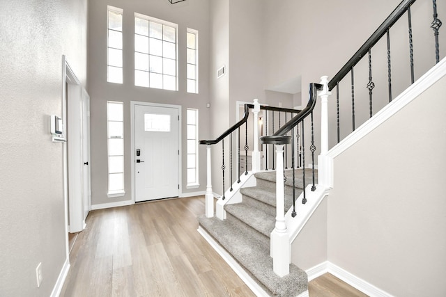 entryway featuring a towering ceiling and light hardwood / wood-style floors