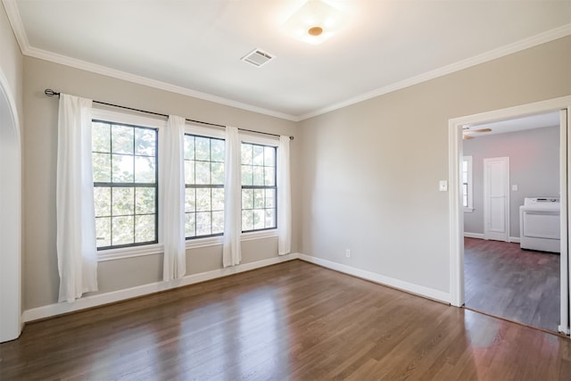 spare room featuring dark hardwood / wood-style flooring, ornamental molding, and washer / dryer