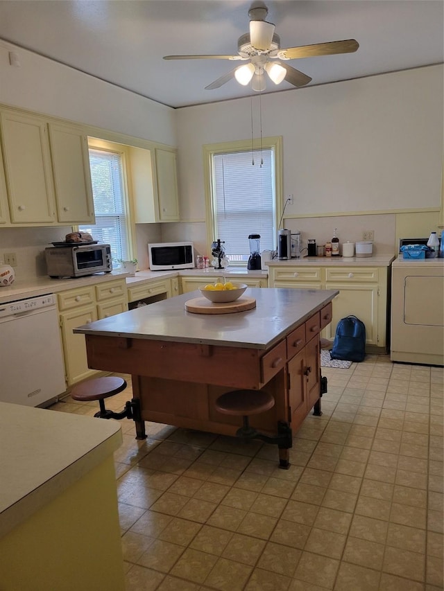 kitchen featuring cream cabinetry, white appliances, washer / clothes dryer, and ceiling fan