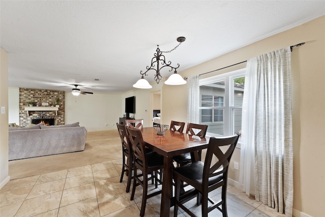 dining space with ceiling fan, light colored carpet, a textured ceiling, and a brick fireplace