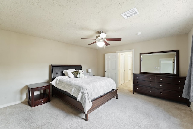 bedroom with ceiling fan, light colored carpet, and a textured ceiling