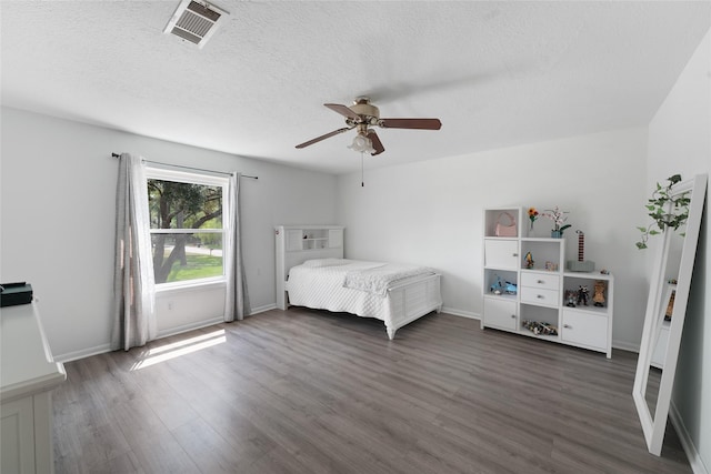 bedroom featuring a textured ceiling, dark hardwood / wood-style floors, and ceiling fan