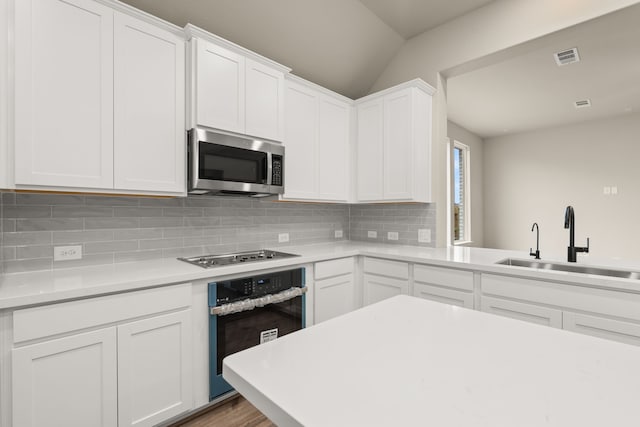 kitchen with decorative backsplash, white cabinetry, sink, and appliances with stainless steel finishes