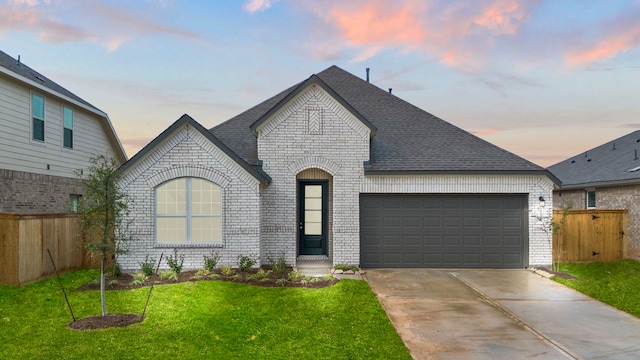 french country home featuring a garage and a yard