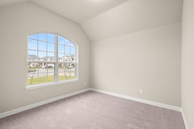 carpeted empty room featuring vaulted ceiling