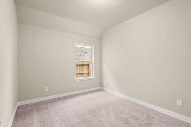 carpeted empty room featuring vaulted ceiling