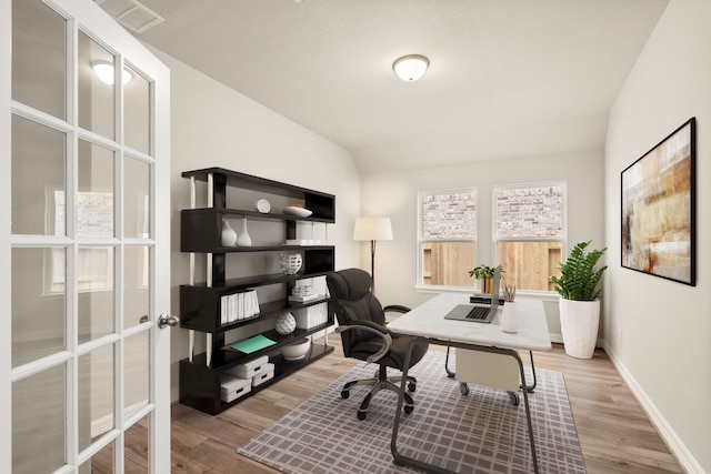 home office featuring light hardwood / wood-style floors and vaulted ceiling