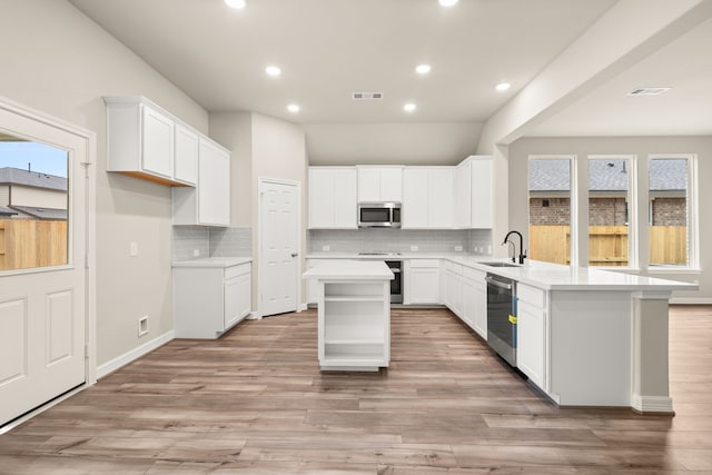 kitchen featuring light wood-type flooring, appliances with stainless steel finishes, a center island, and plenty of natural light