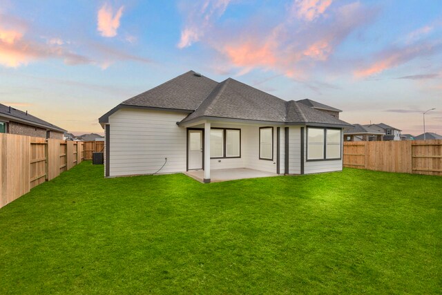 back house at dusk with a lawn and a patio