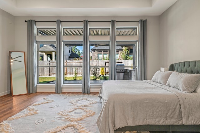 bedroom with access to outside, multiple windows, and hardwood / wood-style flooring