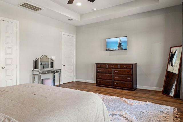 bedroom featuring dark hardwood / wood-style floors, a raised ceiling, and ceiling fan