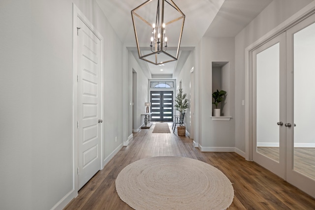 corridor with a chandelier, dark wood-type flooring, and french doors