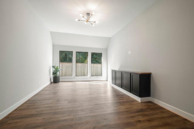 unfurnished room featuring a chandelier, dark hardwood / wood-style floors, and vaulted ceiling