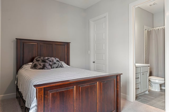 bedroom with ensuite bathroom and light hardwood / wood-style flooring