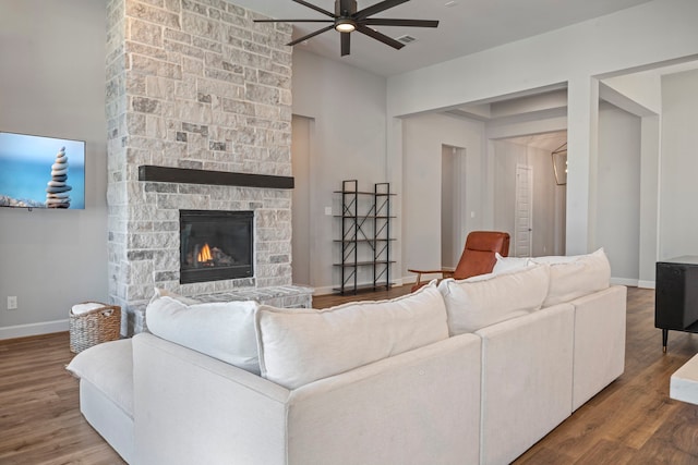 living room featuring a stone fireplace, ceiling fan, and hardwood / wood-style flooring