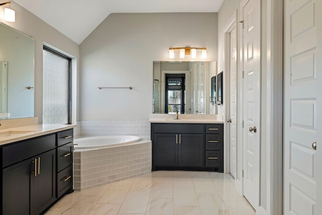 bathroom featuring tiled tub, vanity, and lofted ceiling