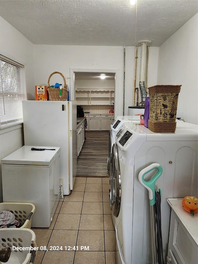 washroom featuring light tile patterned flooring, washer and dryer, and a textured ceiling