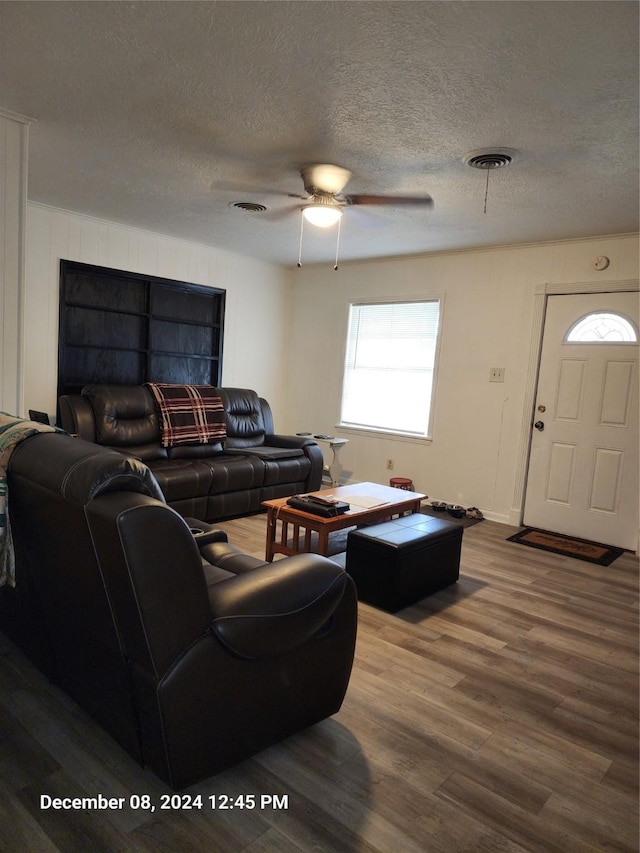 living room featuring hardwood / wood-style floors, ceiling fan, and a textured ceiling