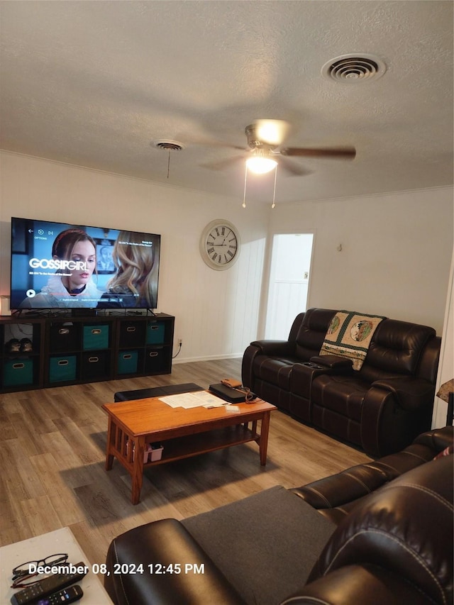 living room featuring hardwood / wood-style floors, ceiling fan, and a textured ceiling