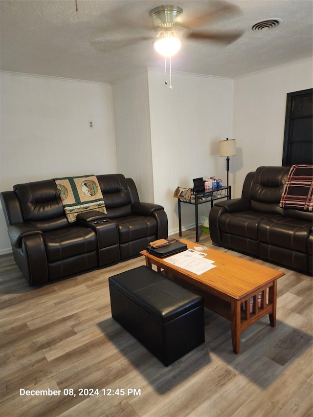 living room with hardwood / wood-style flooring, ceiling fan, and a textured ceiling