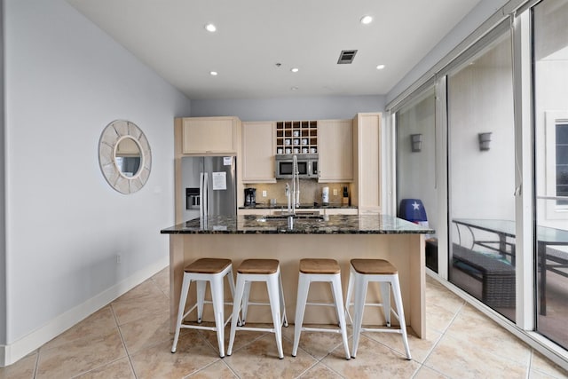 kitchen featuring sink, an island with sink, stainless steel appliances, and dark stone countertops