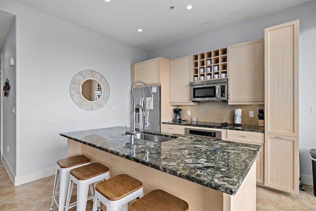 kitchen with decorative backsplash, stainless steel appliances, a center island with sink, and sink