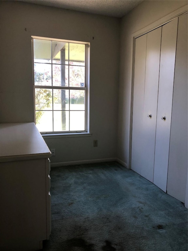 unfurnished bedroom with dark carpet, a closet, and a textured ceiling